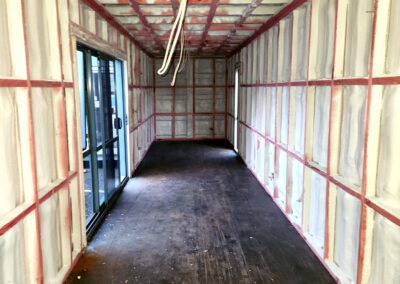 Wide view of container interior spray foamed on walls and ceiling with red framing